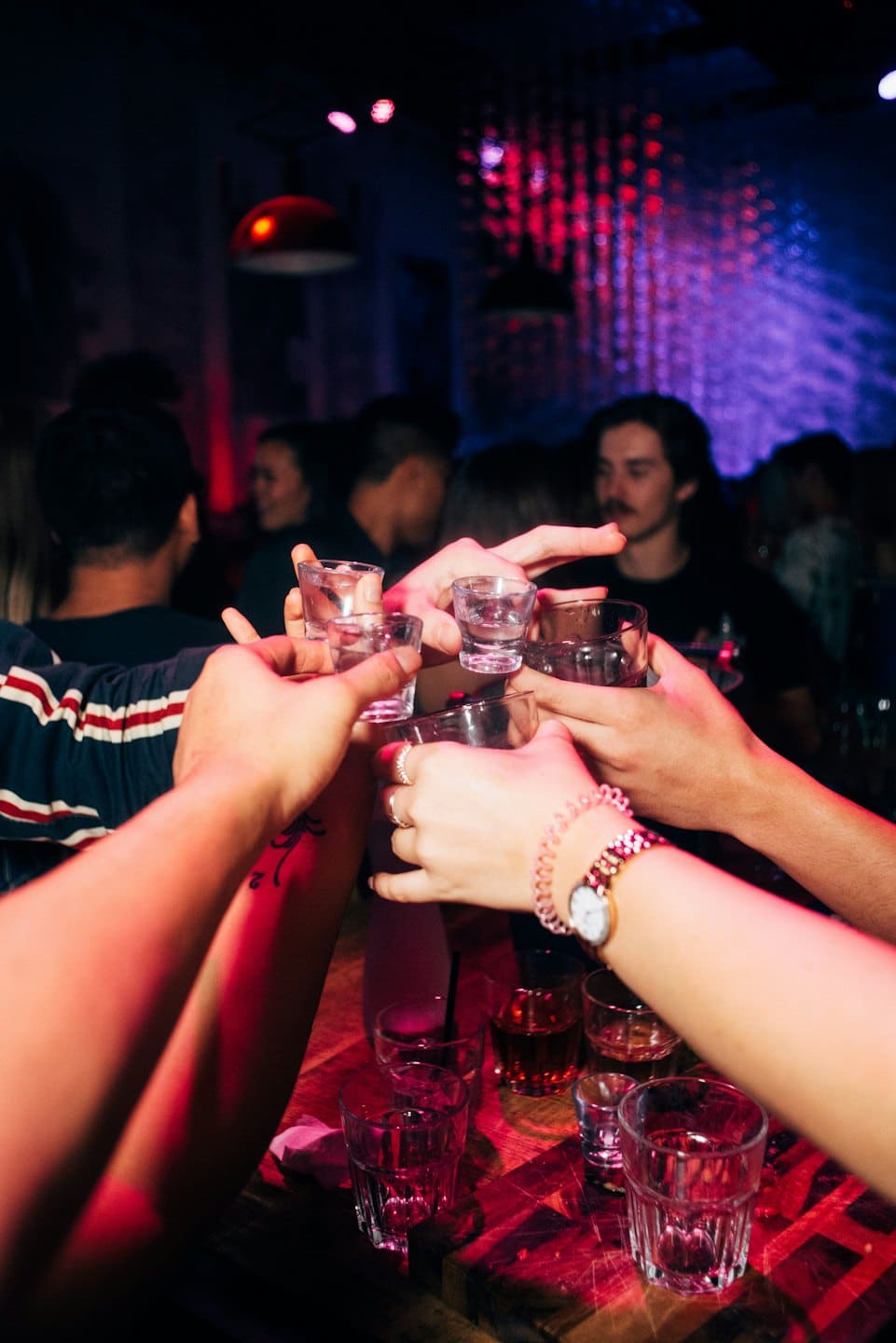 Hands holding shot glasses raising in a celebratory toast.