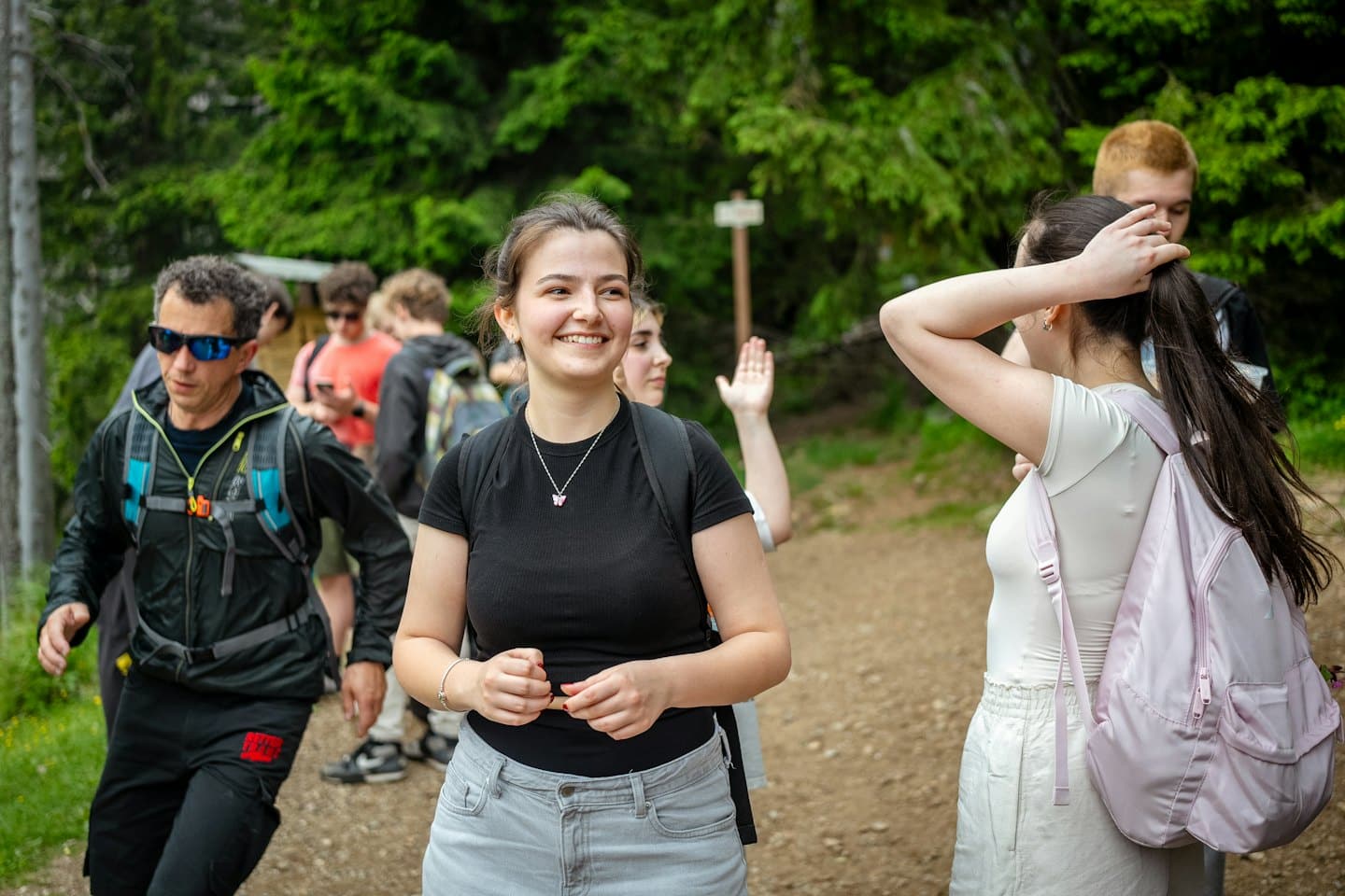 A group of hikers walks along a dirt forest trail.
