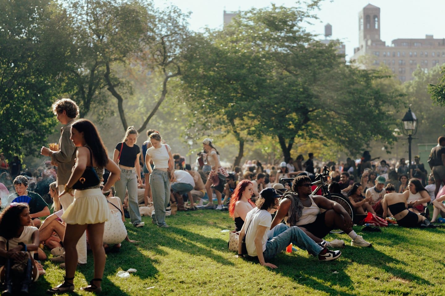 People relax and socialize on the grass in a park.